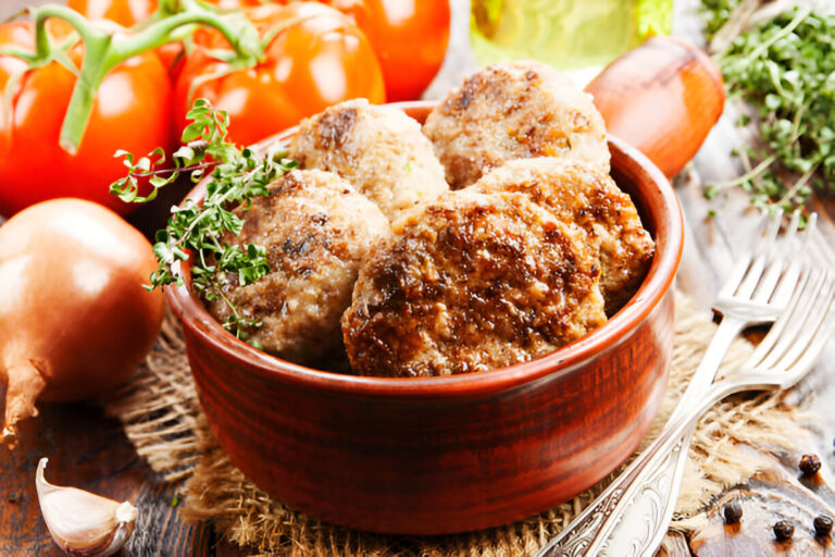 Golden crispy beef cutlet served with dipping sauce and fresh herbs.